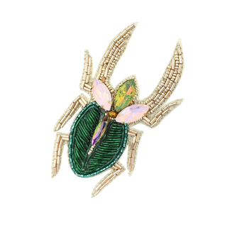 Decorative brooch with gold, green, and pink elements on a white background